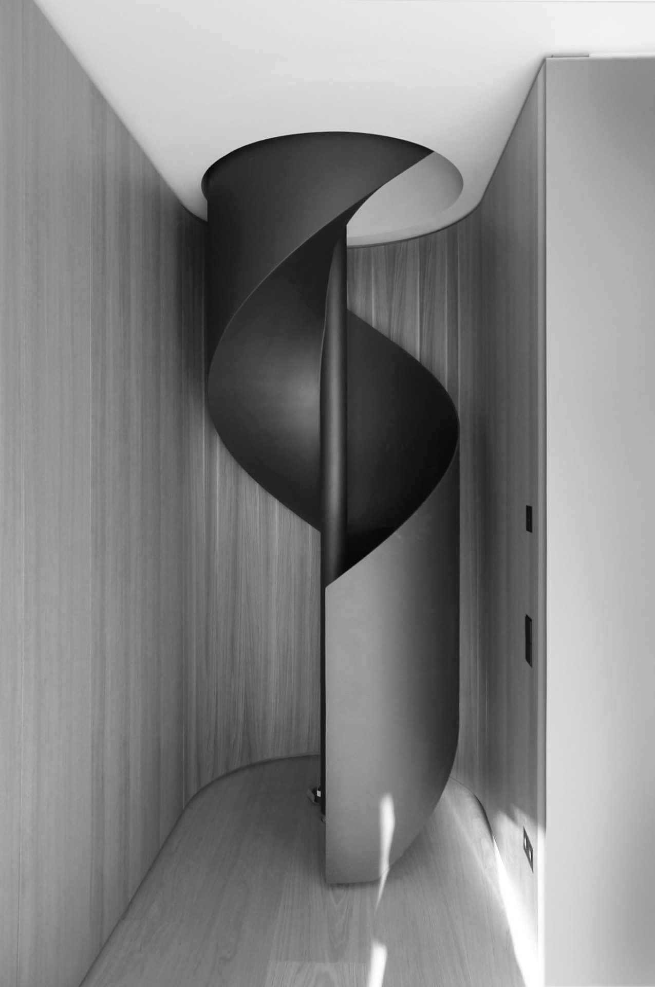 Schwarze Wendeltreppe in hellem Innenraum mit Holzverkleidung